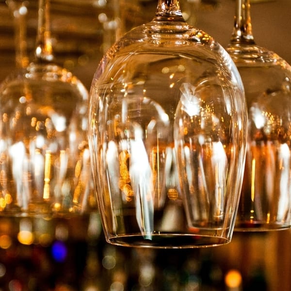 Row of sparkling wine glasses hanging upside down in a dimly lit bar or restaurant.